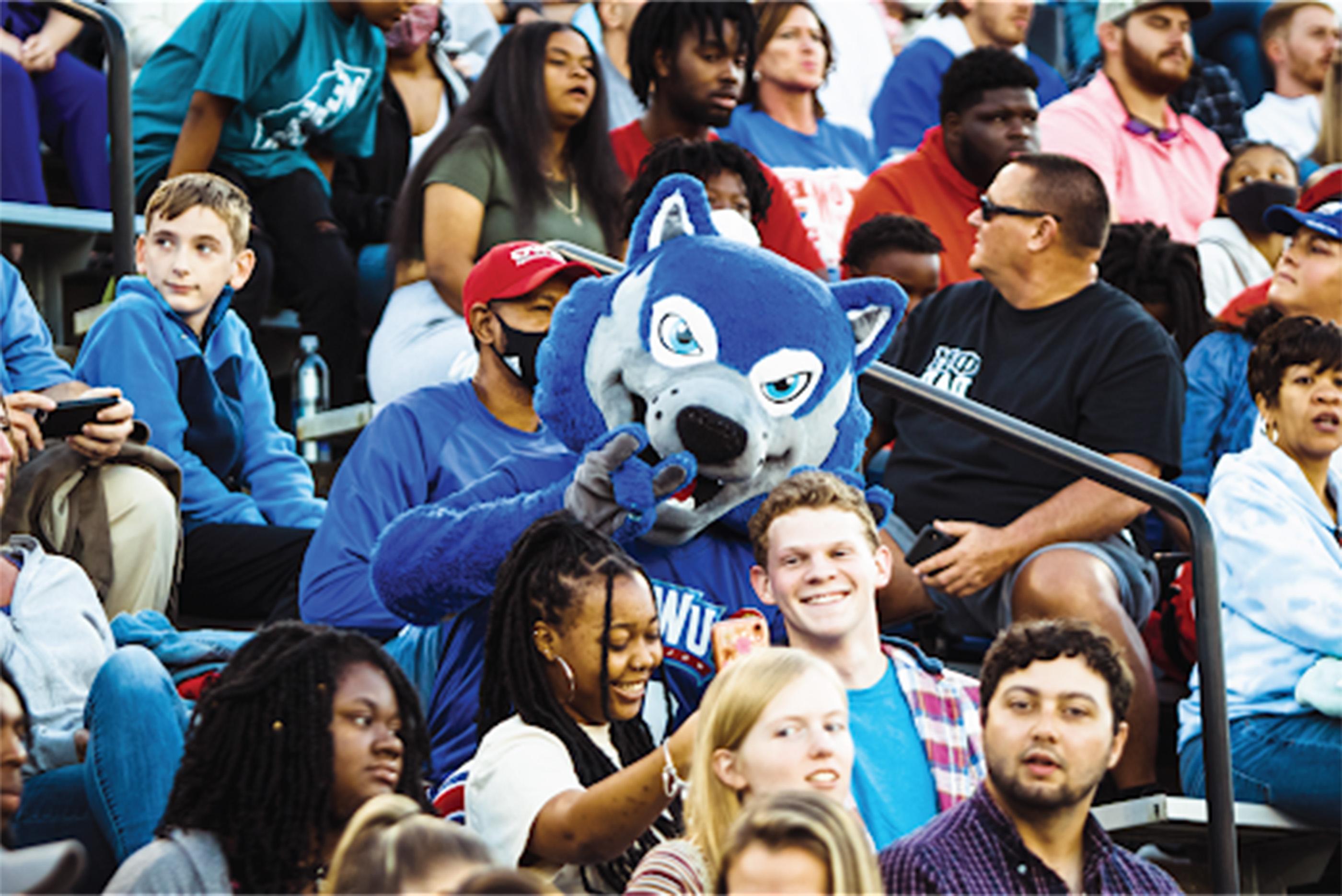 wolfie in a crowd with students and parents and friends at the stadium
