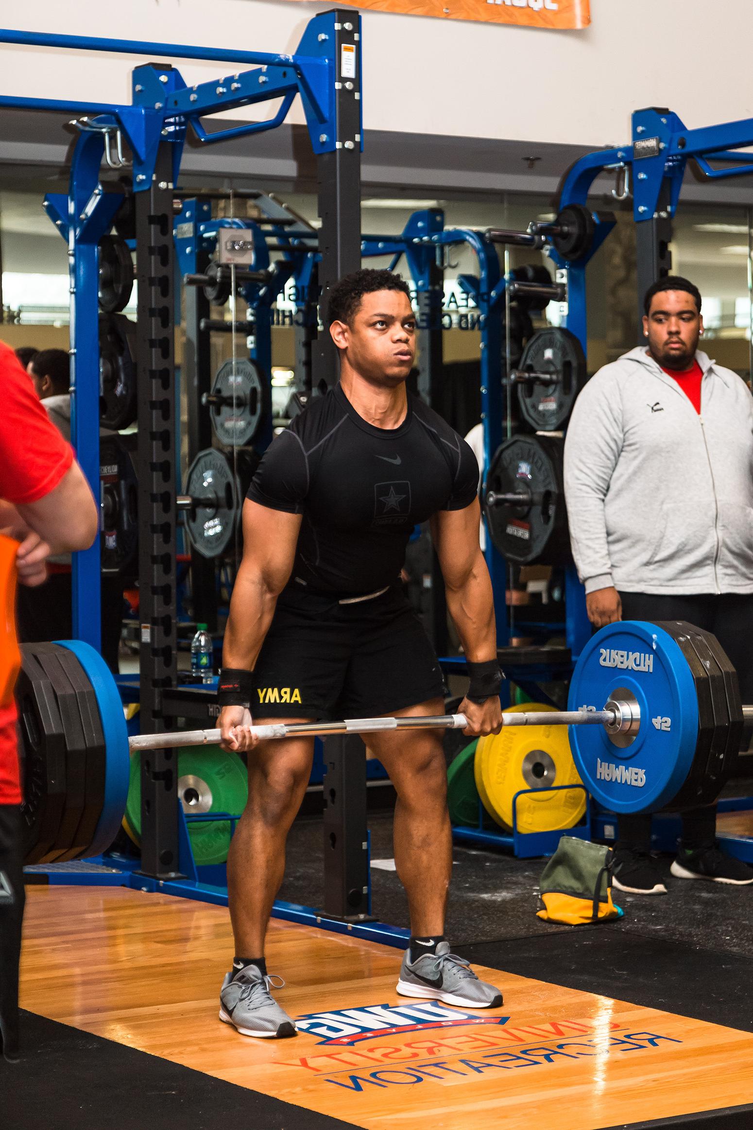 Student with army shorts doing a deadlift at the Campus Center during a powerlifting competition